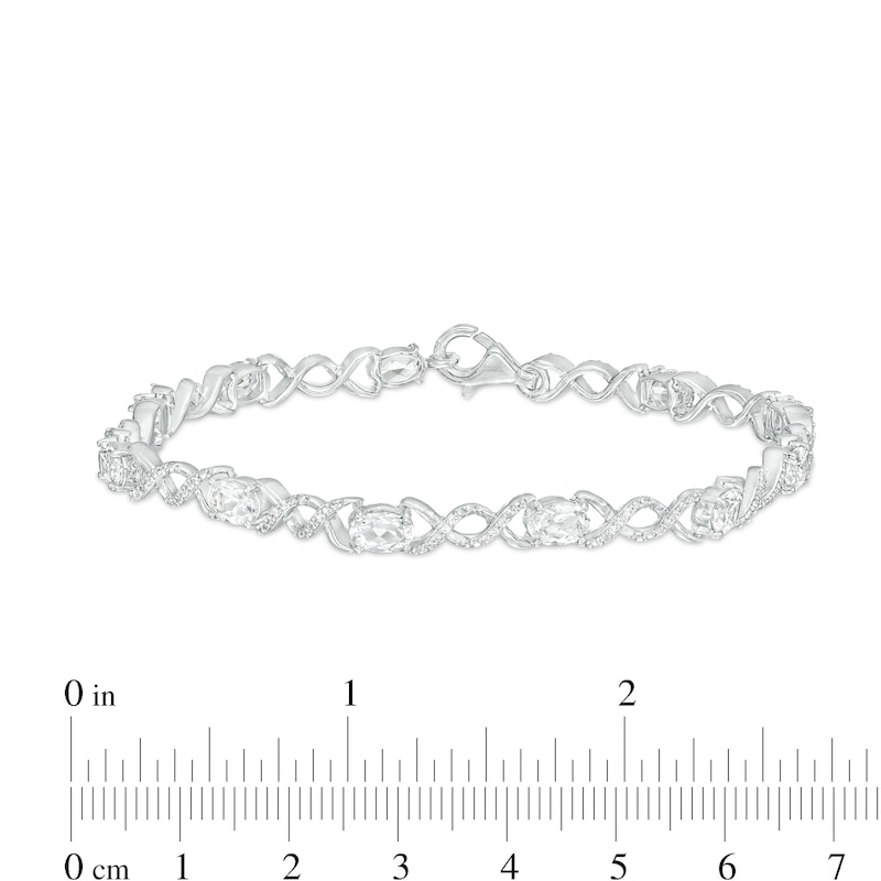 Oval White Lab-Created Sapphire and 0.18 CT. T.W. Diamond Infinity Ribbon Link Line Bracelet in Sterling Silver – 7.5"