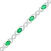 Thumbnail Image 0 of Oval Lab-Created Emerald and 0.18 CT. T.W. Diamond Infinity Ribbon Link Line Bracelet in Sterling Silver – 7.5"