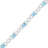 Thumbnail Image 0 of Oval Blue Topaz and 0.18 CT. T.W. Diamond Infinity Ribbon Link Line Bracelet in Sterling Silver – 7.5"