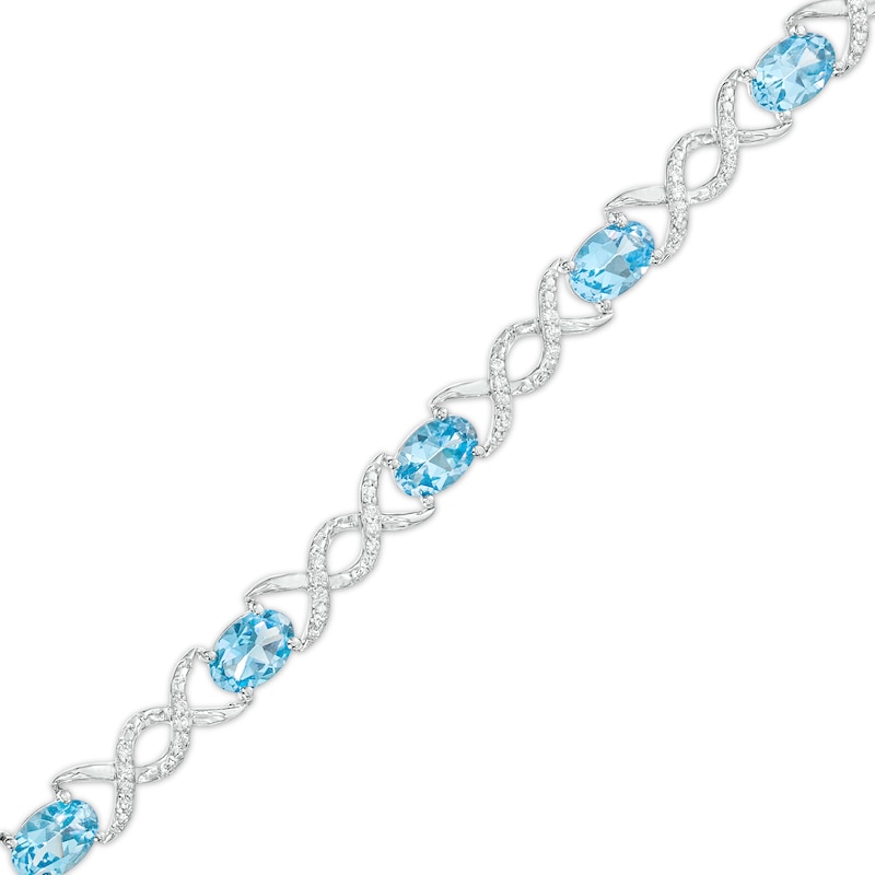 Oval Blue Topaz and 0.18 CT. T.W. Diamond Infinity Ribbon Link Line Bracelet in Sterling Silver – 7.5"