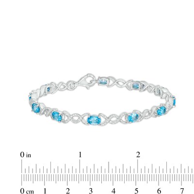 Oval Blue Topaz and 0.18 CT. T.W. Diamond Infinity Ribbon Link Line Bracelet in Sterling Silver – 7.5"