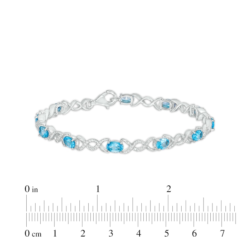 Oval Blue Topaz and 0.18 CT. T.W. Diamond Infinity Ribbon Link Line Bracelet in Sterling Silver – 7.5"